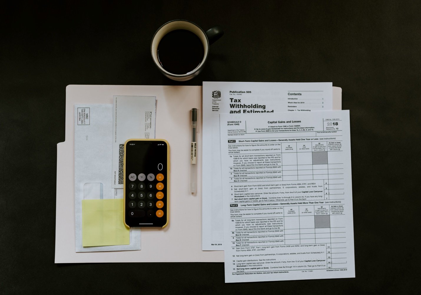 Tax papers, iPhone, pen and a mug on a surface