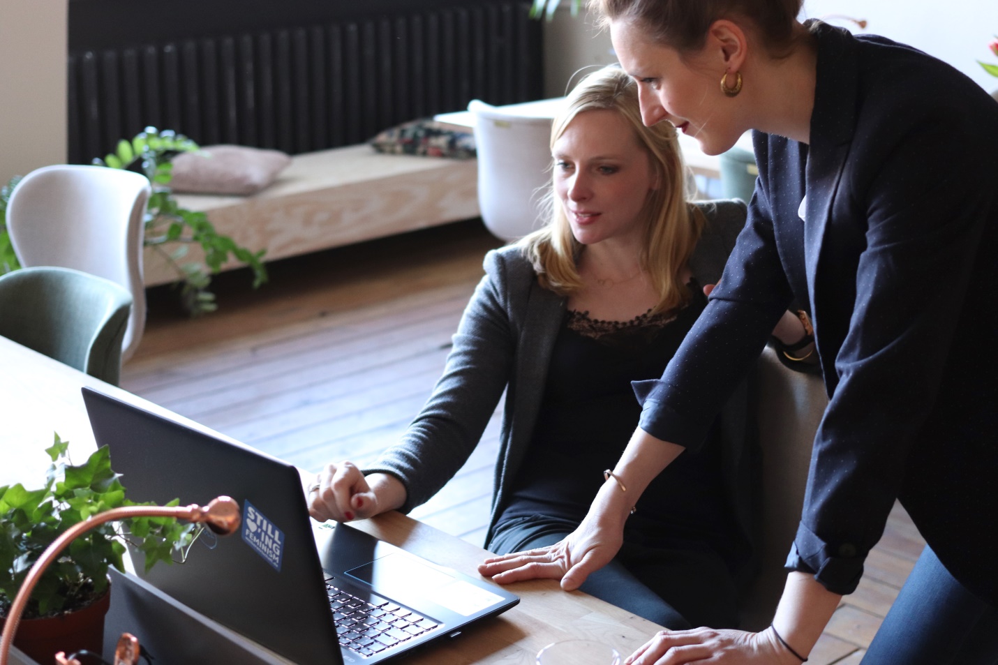 Two women looking at a black laptop