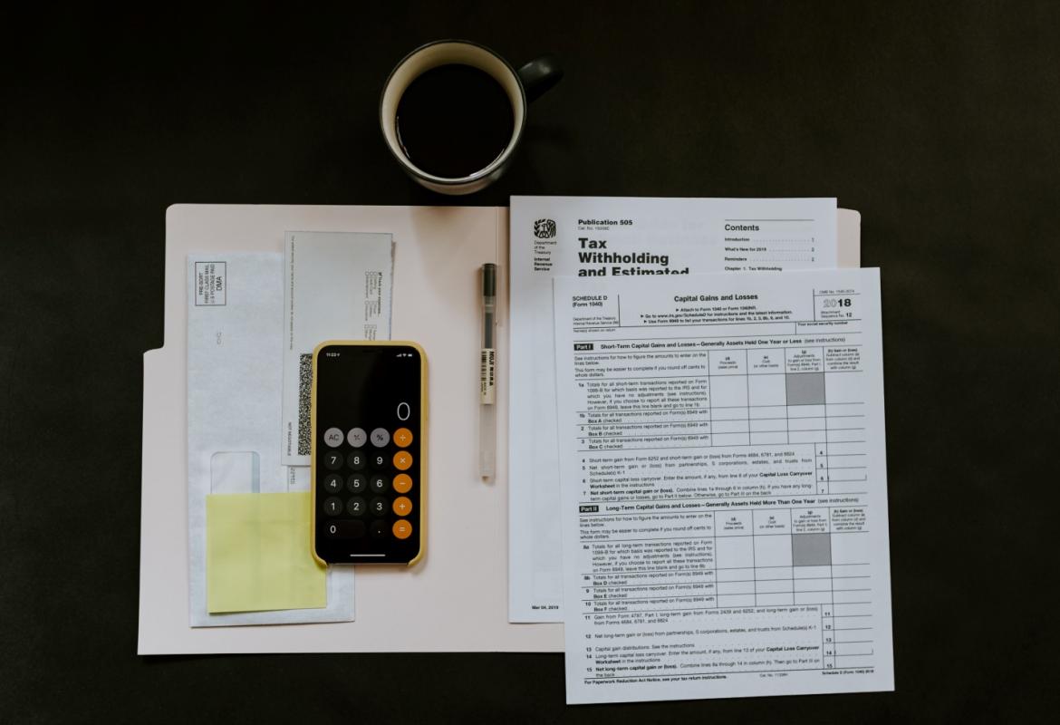 Tax papers, iPhone, pen and a mug on a surface