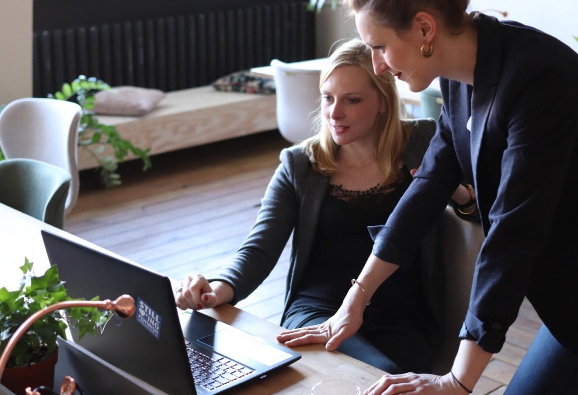 Two women looking at a black laptop