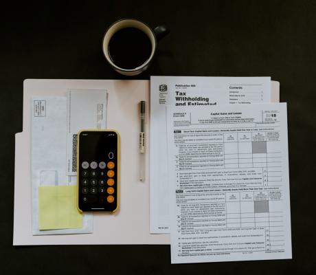 Tax papers, iPhone, pen and a mug on a surface