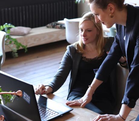 Two women looking at a black laptop