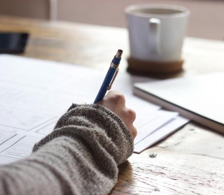 A person writing with a pen on paper 