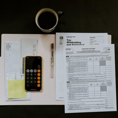 Tax papers, iPhone, pen and a mug on a surface