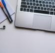 silver laptop computer beside white ruled paper